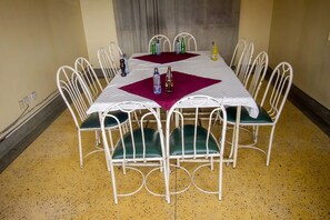 A dining table with a white metal frame and green cushioned chairs, set with water bottles and a bottle of soda. - Seldom Hotel (Nairobi)