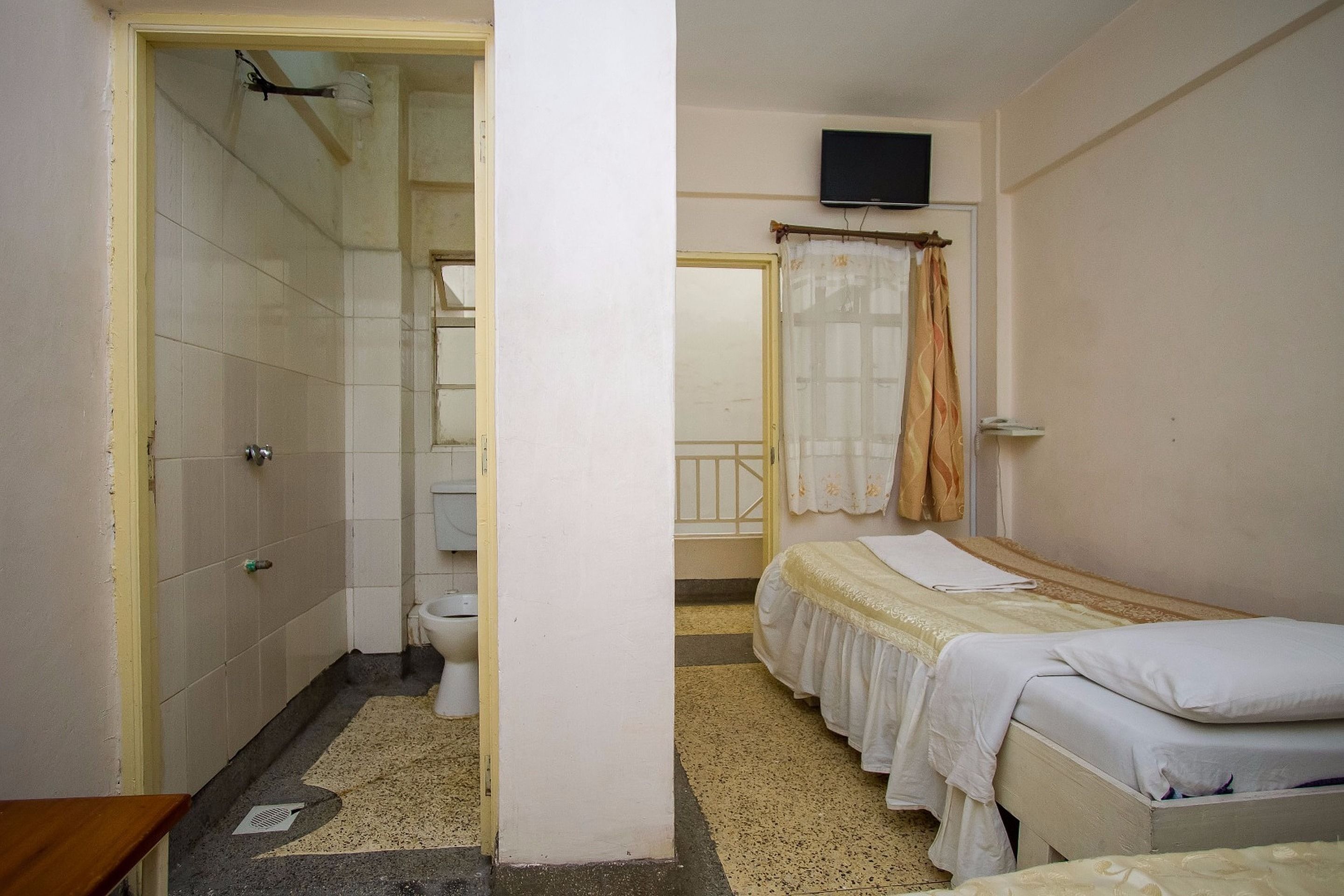 A room with a bed, a toilet, and a shower area.