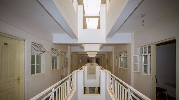A long, narrow hallway with white railings and doors on both sides. - Rabi Hotel (Nairobi)
