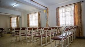 A room with rows of chairs arranged for seating, large windows with curtains, and a ceiling light fixture. - Rabi Hotel (Nairobi)