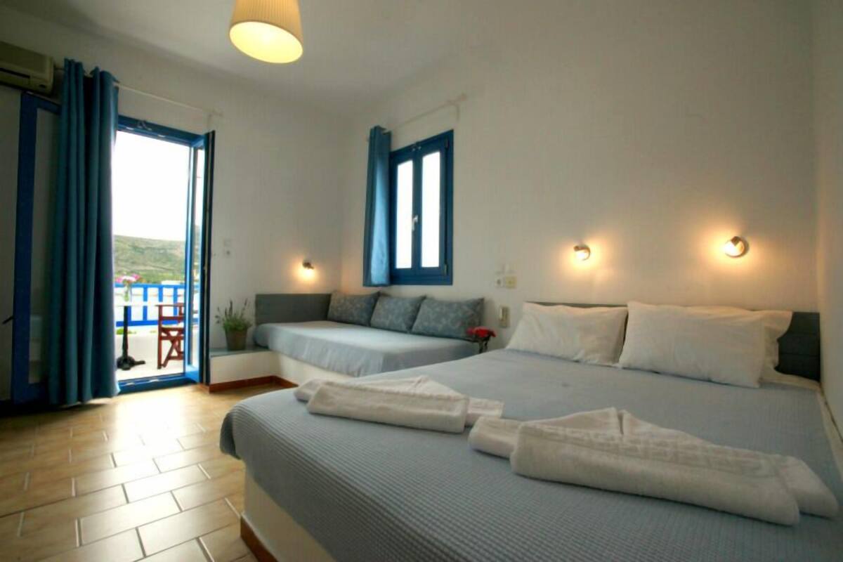 A hotel room with two beds, a balcony, and a view of the outdoors.