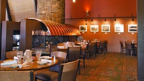 A restaurant with wooden walls, stone pillar, and patterned carpet. Tables are set with plates, glasses, and cutlery.