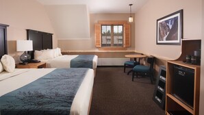 A hotel room with two beds, a desk, a chair, a television, and a window with shutters.