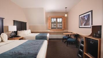 A hotel room with two beds, a desk, a chair, a television, and a window with shutters.