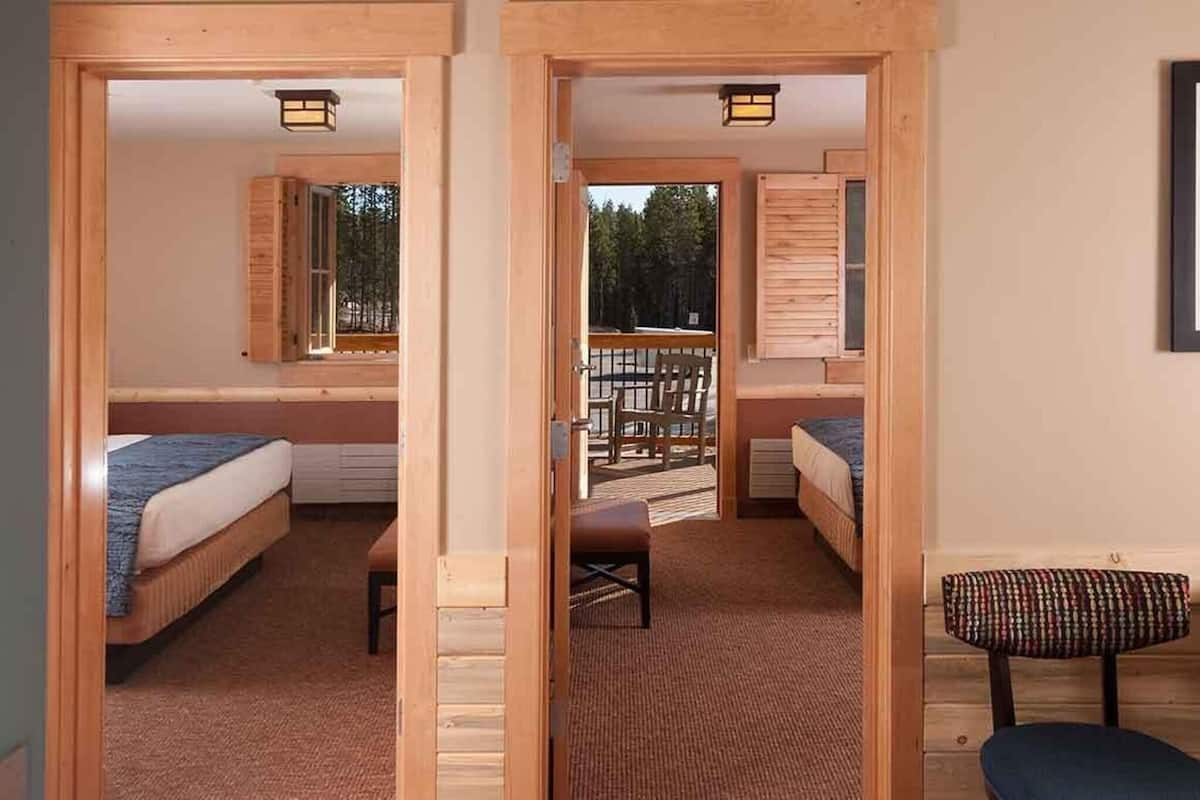 Ein Zimmer mit zwei Betten, einer Bank und Blick auf eine Terrasse.