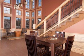 A spacious room with a wooden staircase, large windows, and a chess table.