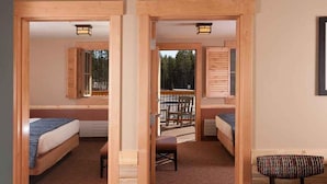 A room with two beds, a bench, and a view of a deck.