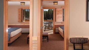 A room with two beds, a bench, and a view of a deck.