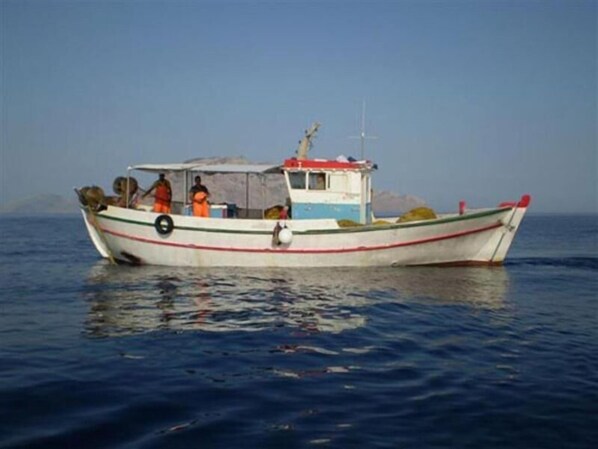 A small boat with a cabin and a covered area, floating on calm water. - Hotel Pelagos (Amorgos)