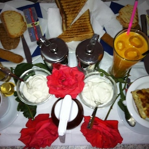 A table with food items, including sandwiches, a drink with a straw, and condiments in jars. - Hotel Pelagos (Amorgos)