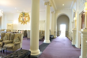 A grand lobby with high ceilings, ornate columns, and a long corridor leading to a door. - Buxted Park Hotel (Uckfield)
