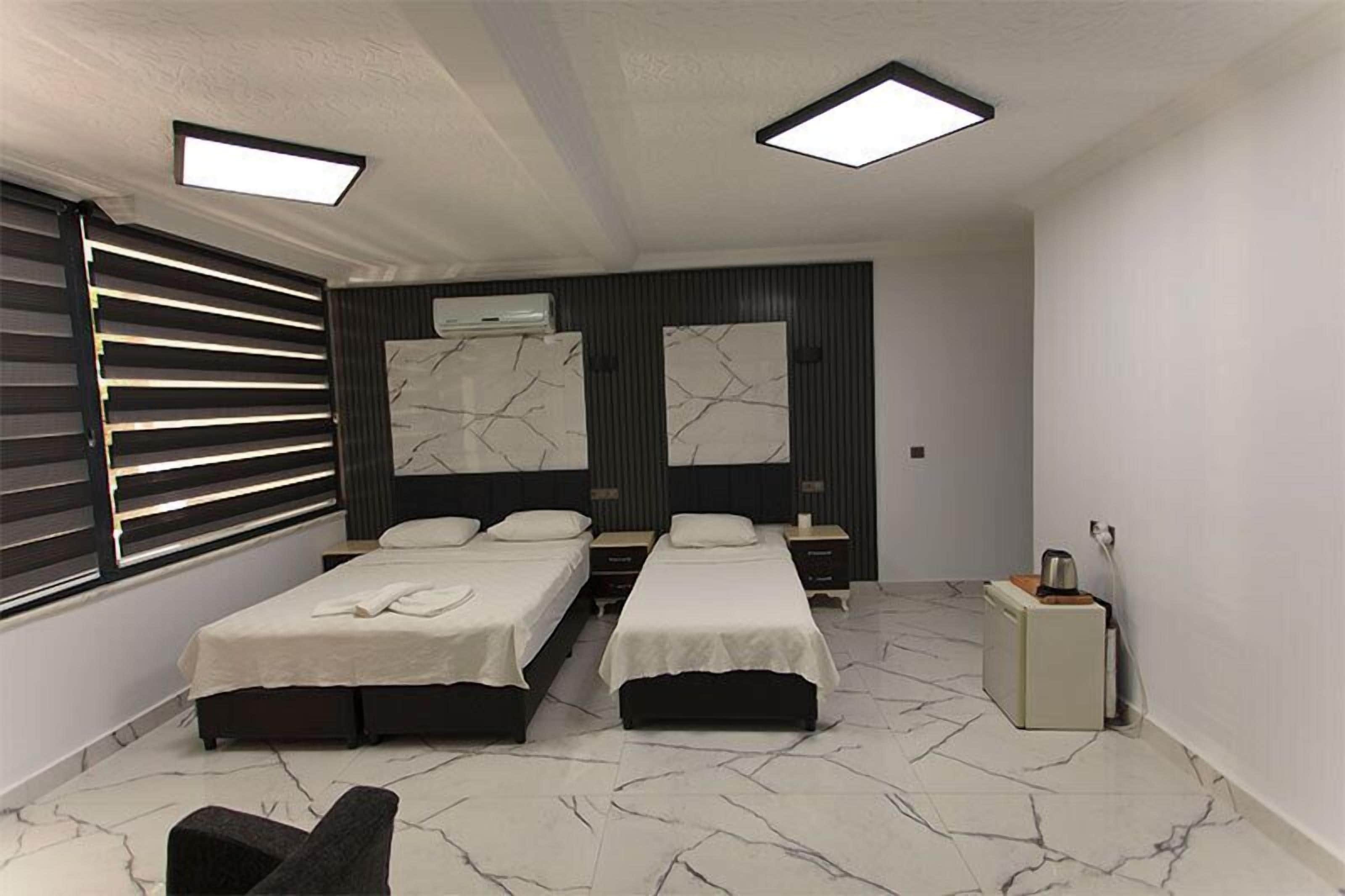 A modern bedroom with two beds, a small seating area, and a nightstand.