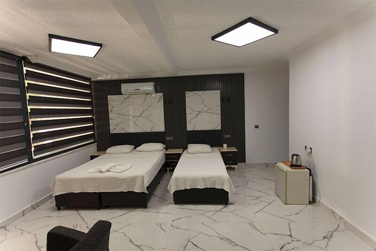 A modern bedroom with two beds, a small seating area, and a nightstand.