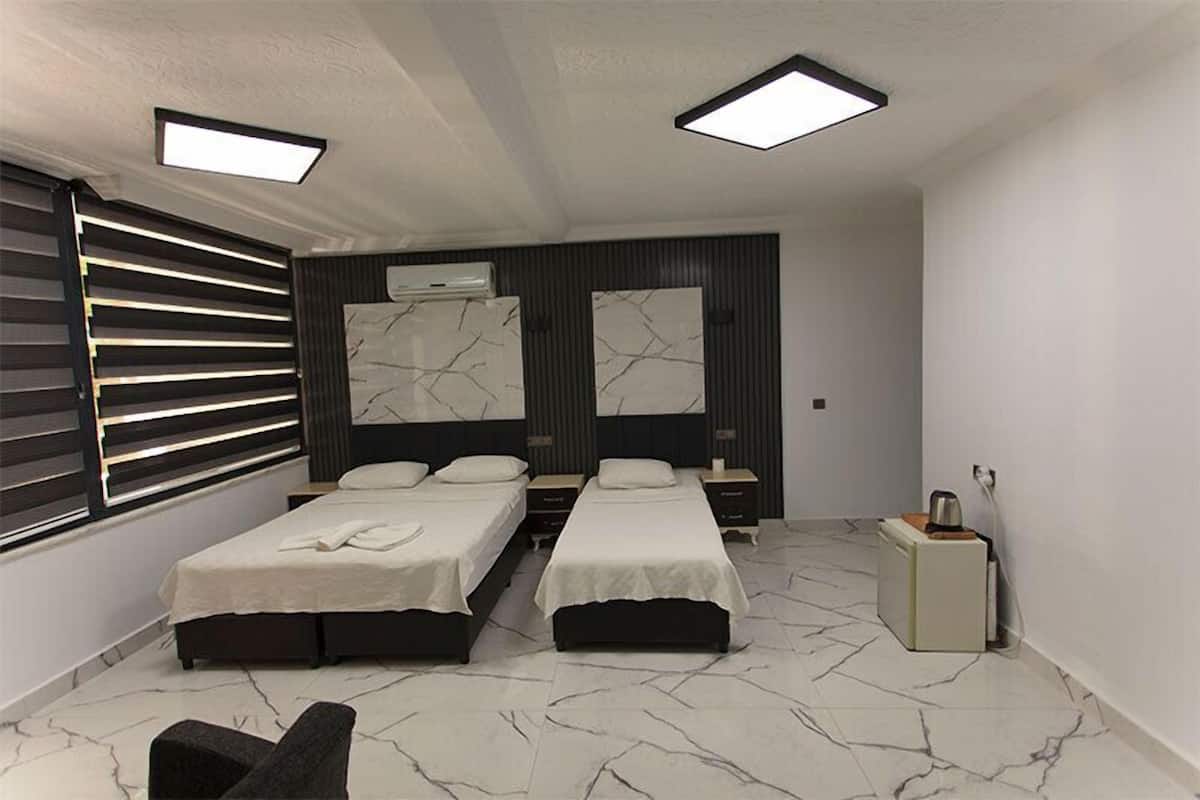 Ein modernes Schlafzimmer mit zwei Betten, einer kleinen Sitzecke und einem Nachttisch.