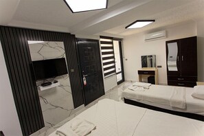 Ein Hotelzimmer mit Fernseher, zwei Betten, einem Schrank, einem Spiegel und einer Tür mit Streifenmuster.