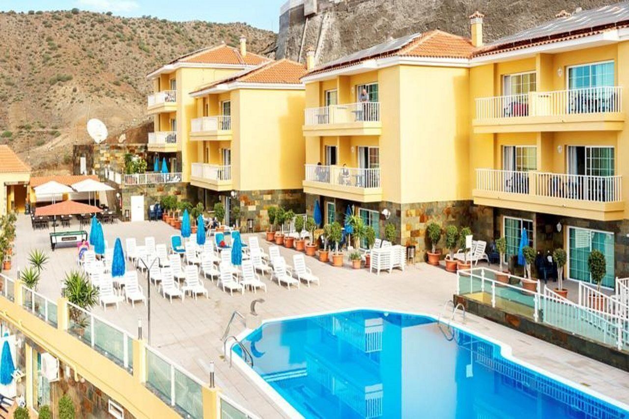 A hotel with a pool area, multiple balconies, and outdoor seating.