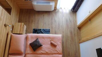 A wooden room with a bed, a window, and an air conditioning unit.