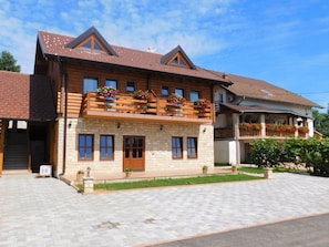 A two-story wooden house with a balcony, stone facade, and a paved driveway. - House Sara 2 (Rakovica)