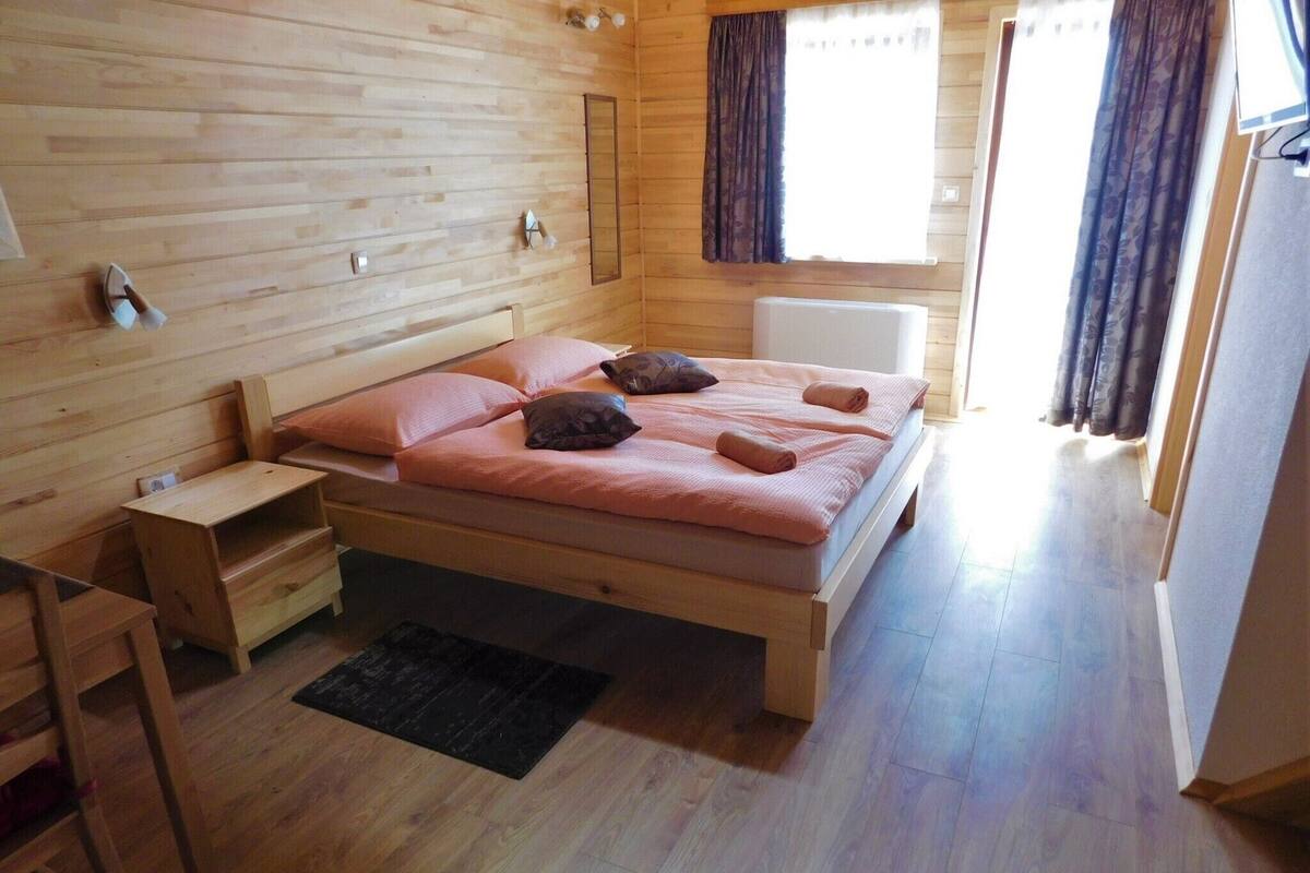 Une pièce en bois avec un lit, une petite table et une fenêtre avec des rideaux.