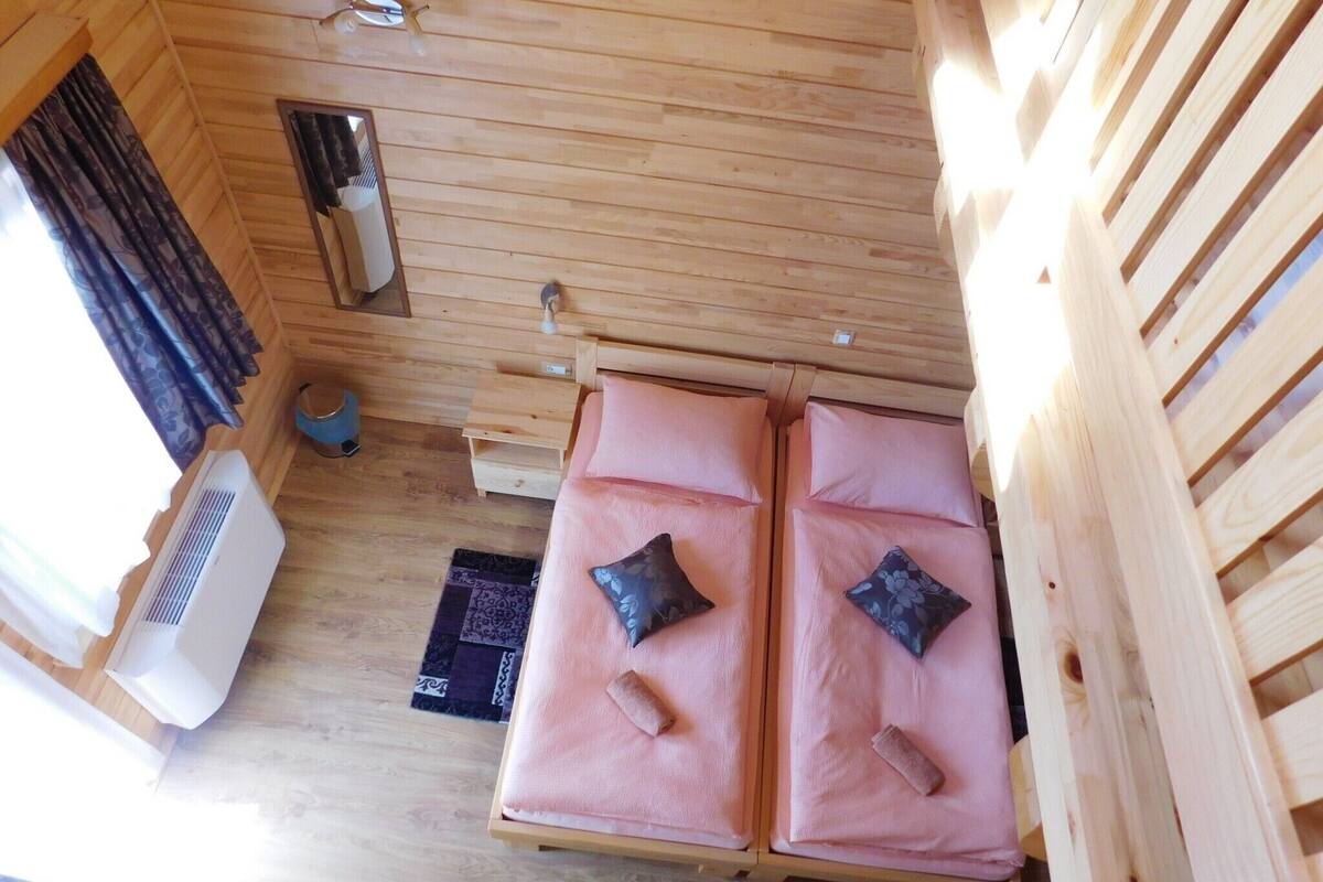 A wooden cabin with a bed, a heater, and a window with curtains.