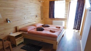 Une pièce en bois avec un lit, une petite table et une fenêtre avec des rideaux.