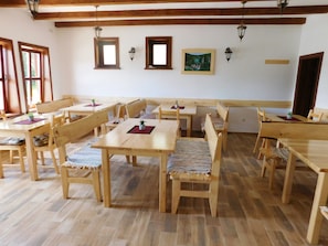 A dining area with wooden tables and benches, a wooden ceiling with exposed beams, and wall-mounted lanterns. - House Sara 2 (Rakovica)