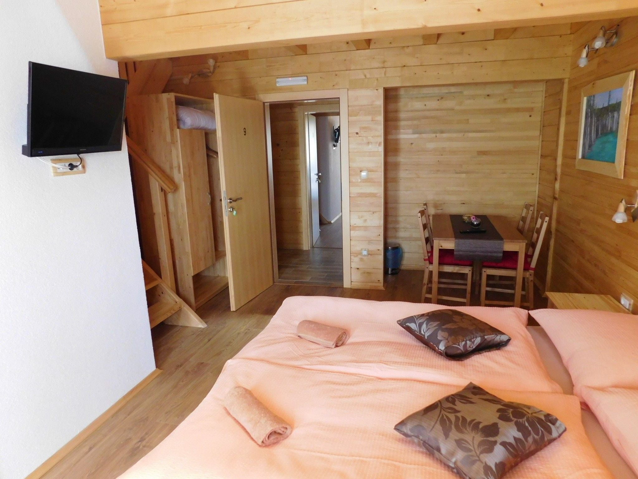 Une pièce de cabane en bois comprenant un lit, un téléviseur, une table à manger et une chaise.
