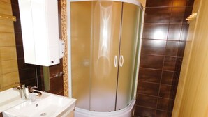 Une salle de bain avec un lavabo blanc, un espace douche et un meuble en bois.