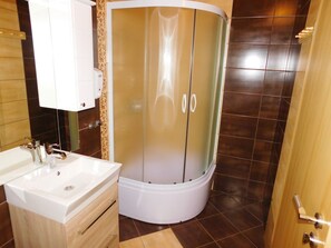 A bathroom with a white sink, a shower enclosure, and a wooden cabinet. - House Sara 2 (Rakovica)