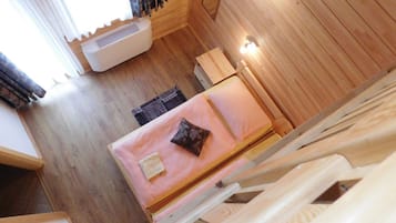 Ein Holzinnenraum mit einem Bett, einem Heizkörper und einem Fenster mit Vorhängen.