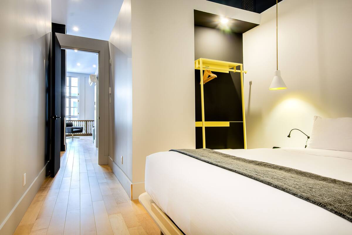 A modern hotel room with a large bed, a walk-in closet, and a view of the outdoor balcony.