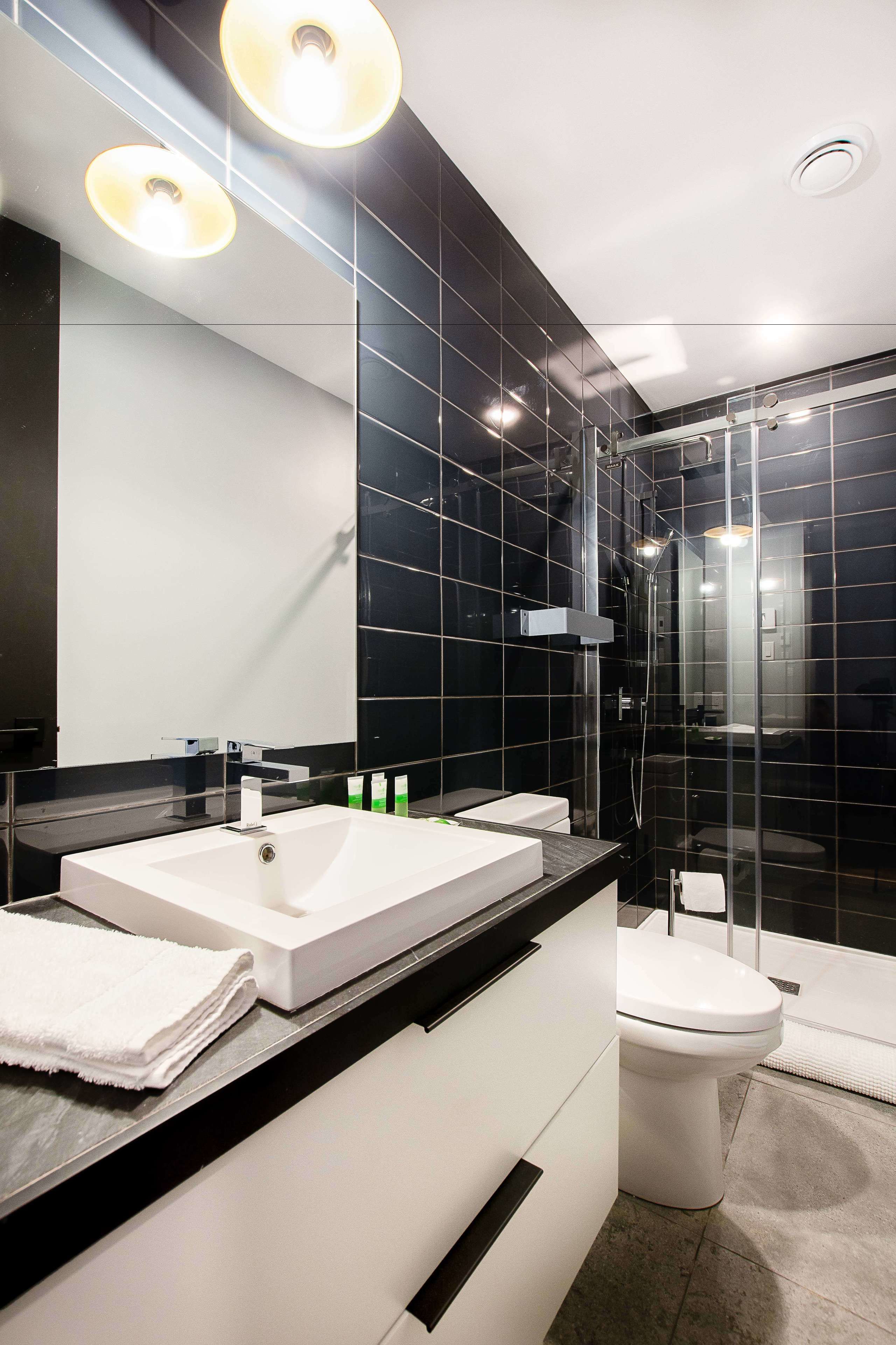 Ein modernes Badezimmer mit einem großen Spiegel, zwei Waschbecken, einer Toilette und einer Duschkabine.