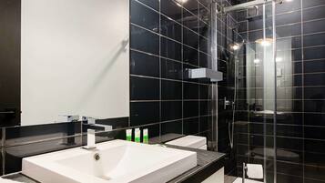 Ein modernes Badezimmer mit einem großen Spiegel, zwei Waschbecken, einer Toilette und einer Duschkabine.