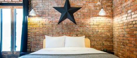 A bed in a room with a brick wall, a star decoration, and two pendant lights.