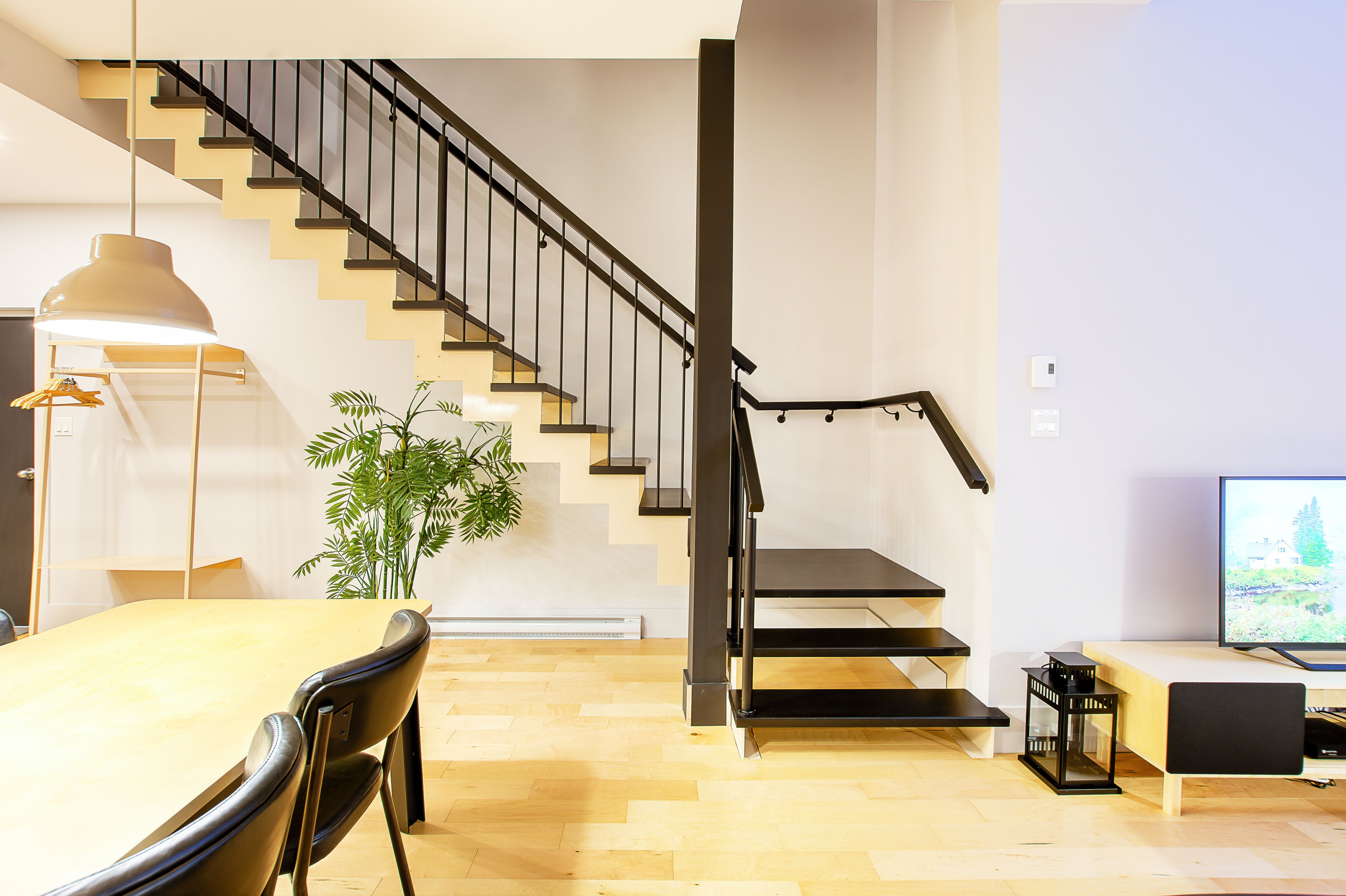 Un espacio moderno para vivir con una escalera, un comedor y una televisión.