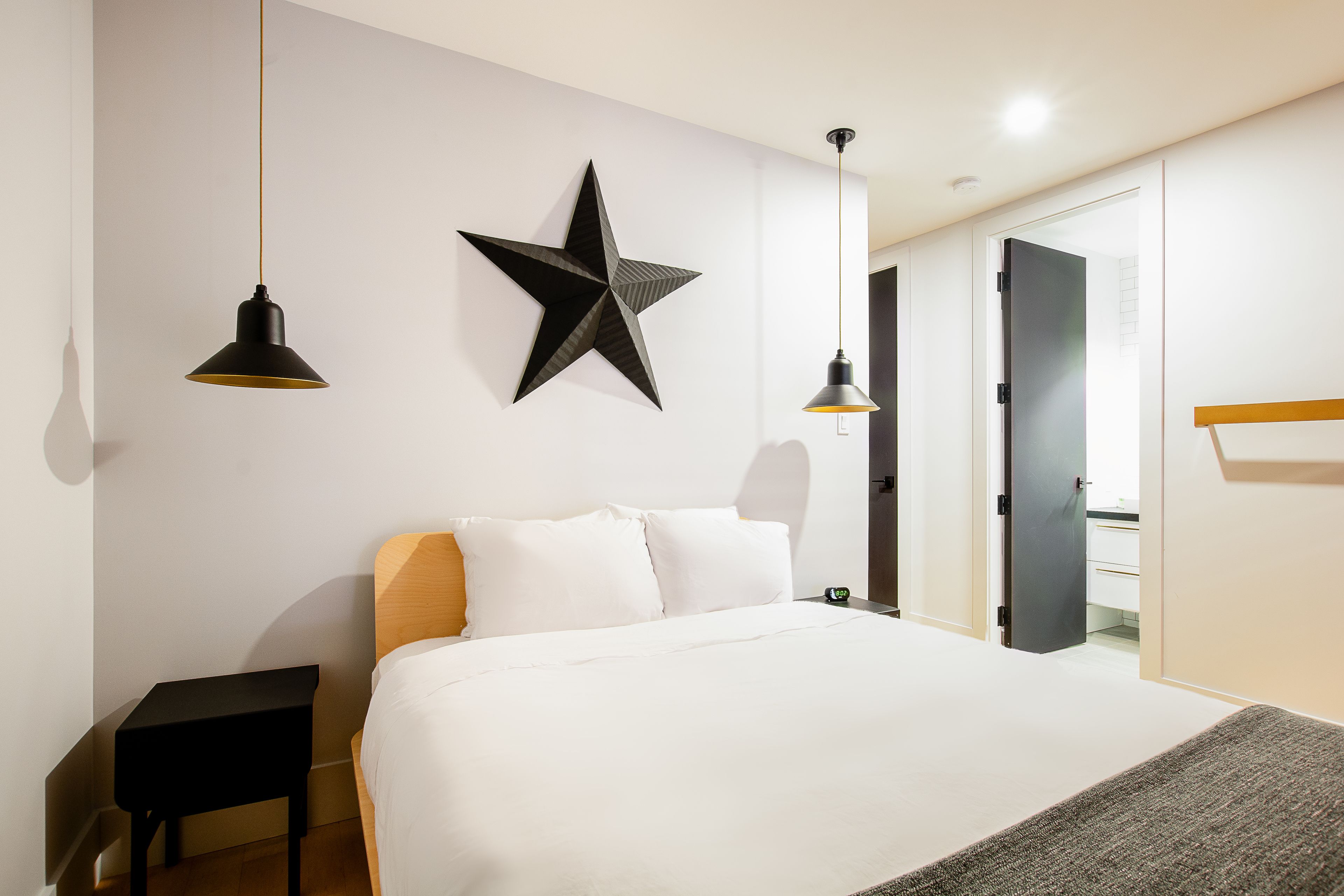 Una habitación de hotel moderna con una cama grande, una decoración de pared con forma de estrella y dos lámparas colgantes.