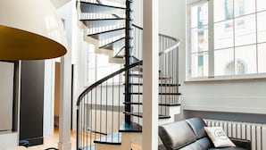 A modern interior with a spiral staircase, a dining area, and a sofa with a view of the city.