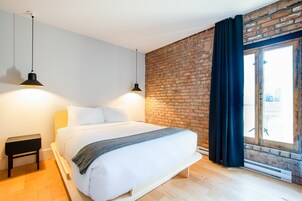 Une chambre moderne avec un mur en briques, un grand lit et deux lampes suspendues.