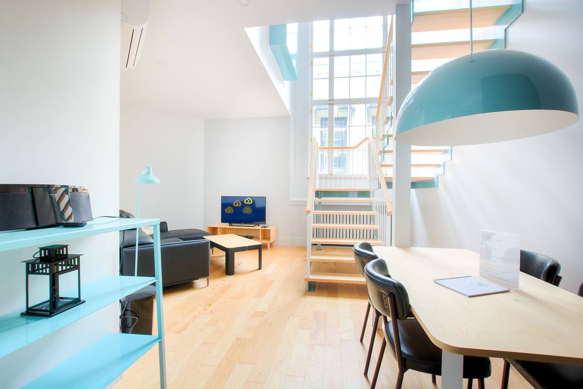 A modern living room with a dining area, a staircase, and a TV.
