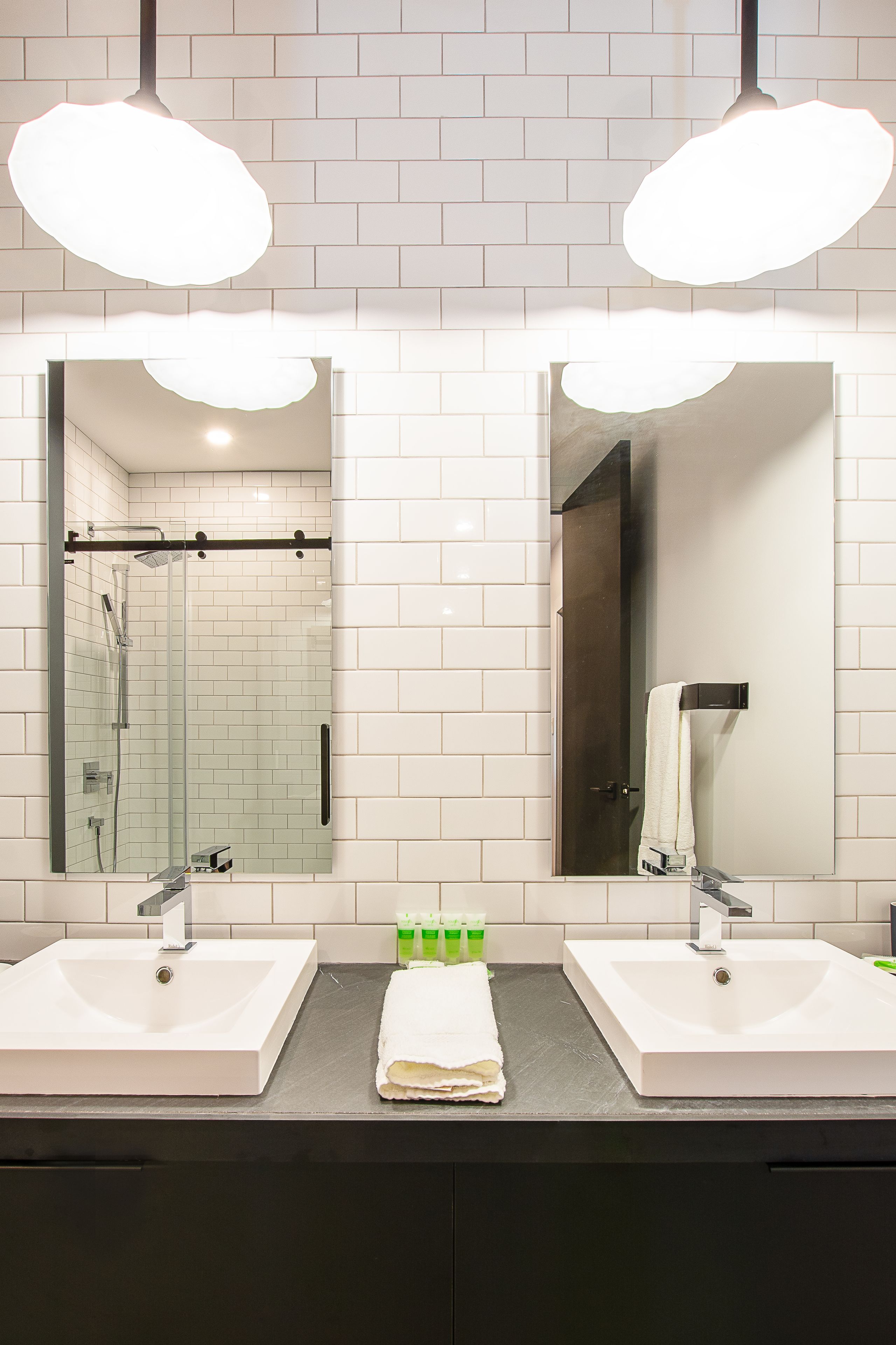 A bathroom with two sinks, a glass shower enclosure, and a large mirror.
