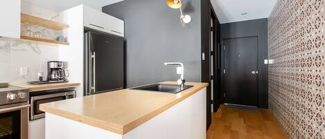 A modern kitchen with a central island, stainless steel appliances, and a patterned wall.