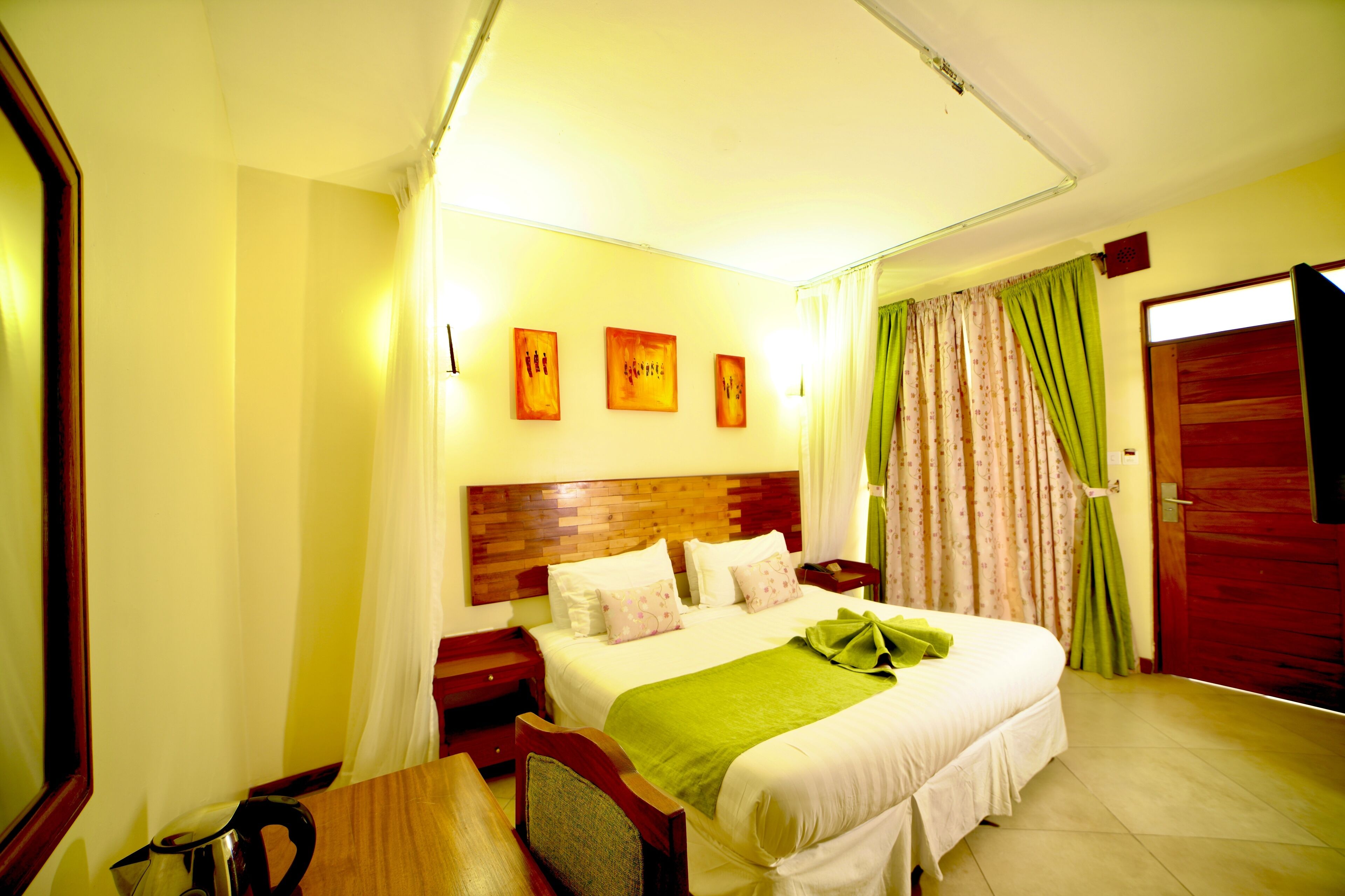 Camera d'albergo con un letto grande, una testiera in legno, un comodino con una lampada e una finestra con tende.