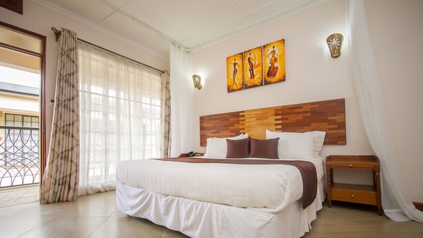 Un dormitorio con una cama grande, cabecera de madera, una mesita de noche y una obra de arte colgada en la pared.