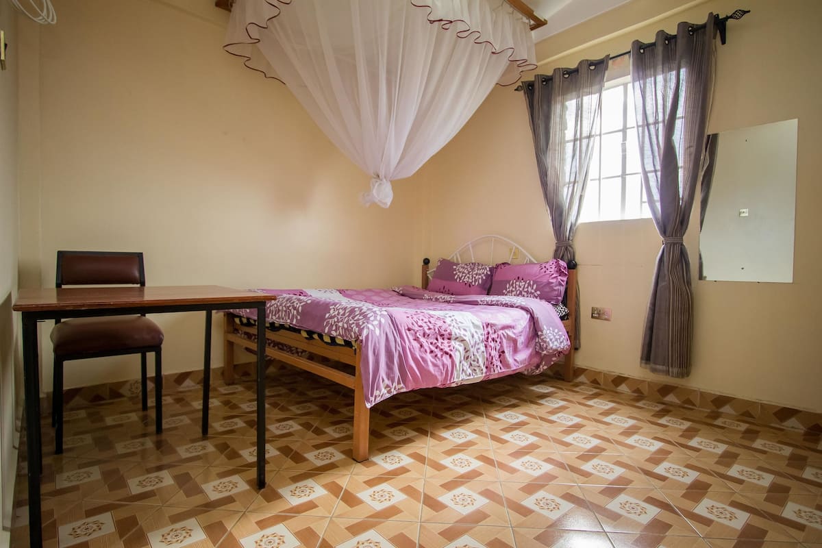A bedroom with a bed, a desk, and a chair.