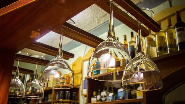 Un espace bar agrémenté de verres à vin suspendus et d’étagères remplies de différentes bouteilles d’alcool.