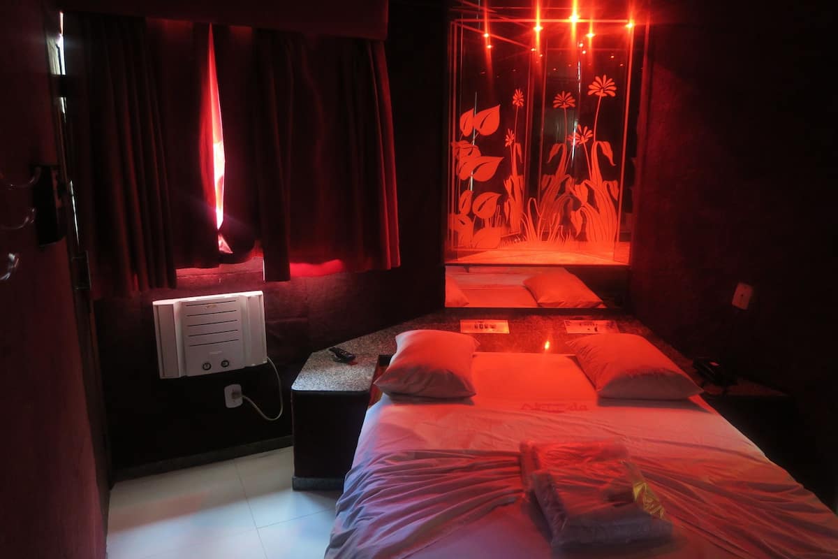 Een zwak verlichte kamer met een bed, een massagetafel en een aan de muur bevestigd massageapparaat.