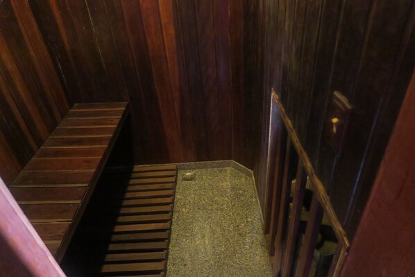 Una escalera de madera estrecha con barandilla de metal y un banco de madera al final.