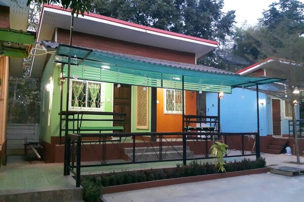 Un piccolo edificio a un piano con una tenda verde e un muro esterno blu.