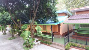 Un edificio con tetto verde, un portico coperto e un piccolo giardino con panchine e piante in vaso.