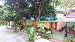 Un edificio con un tetto verde, circondato da alberi e piante. Sono presenti panchine e un vialetto che conduce all'ingresso.